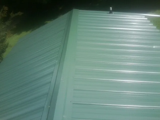 New green metal panels meeting at the ridge of a roof — Flat Roof Repair work by our crew in Canton