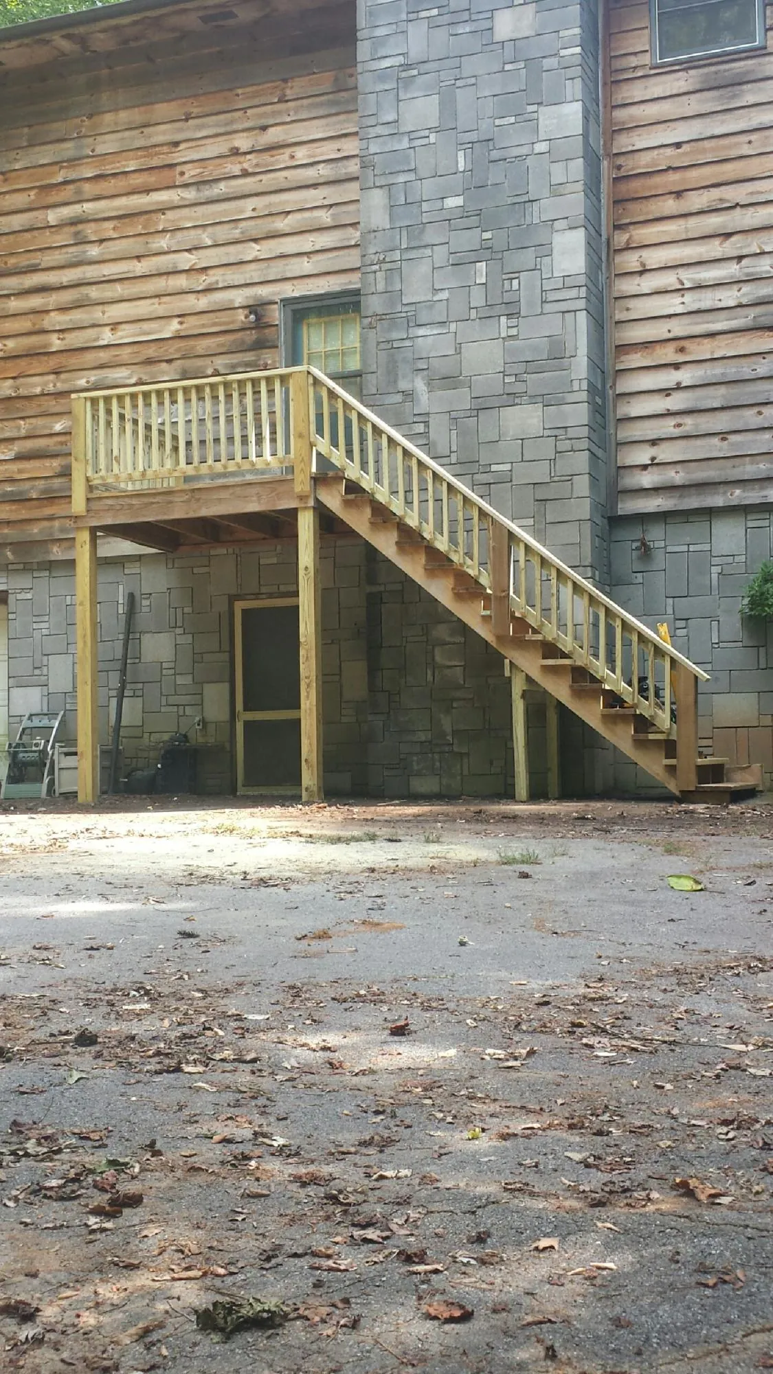 New pressure treated deck and stair landing on a log home in Canton
