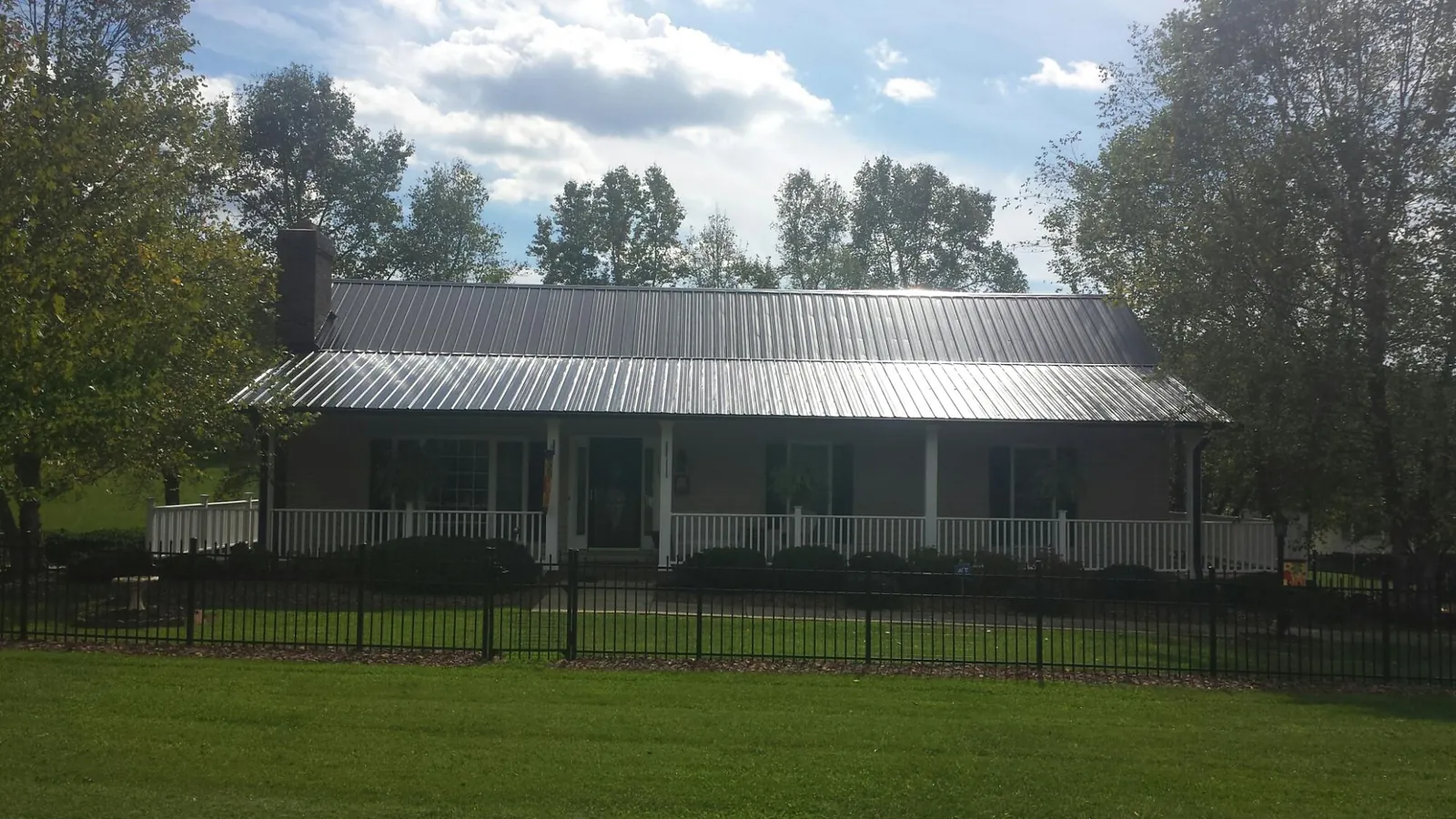 Gray metal roof on a brick ranch with a full width front porch — Gutter Guard Installation work by our crew in Canton