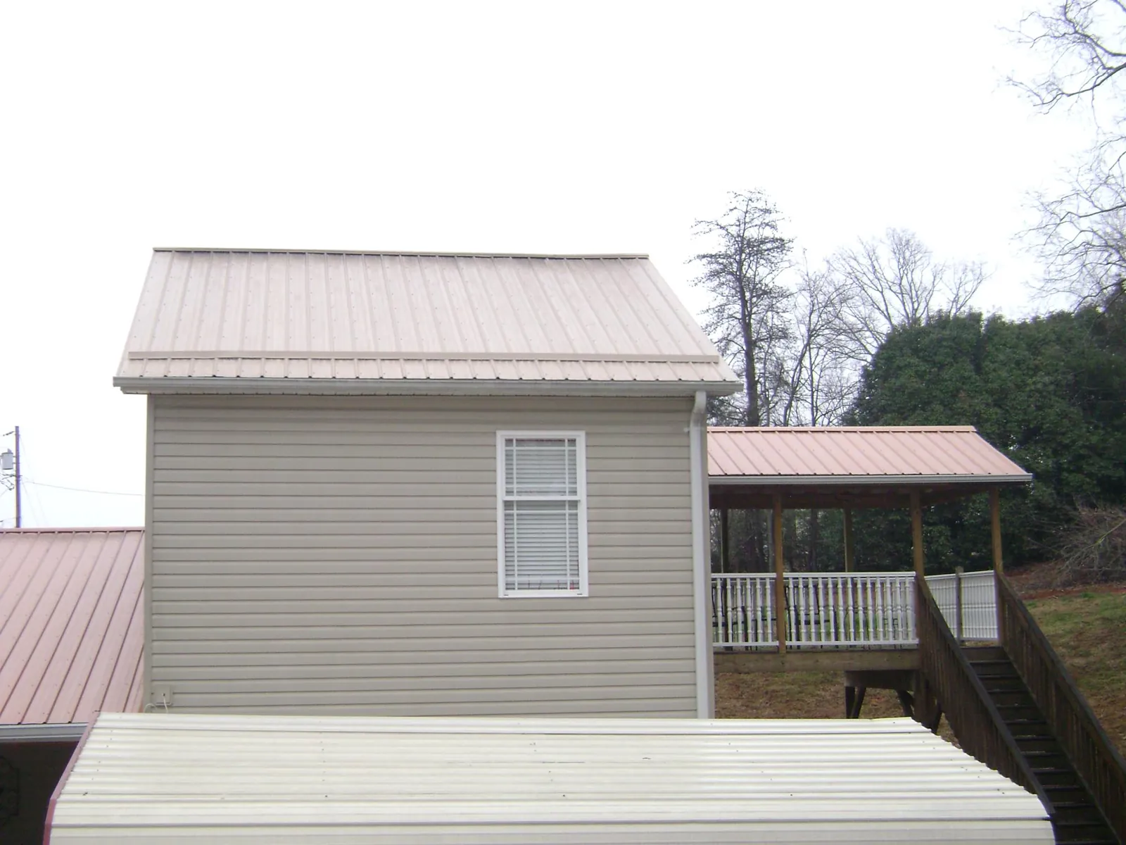 Tan metal roofs on a two story addition and attached porch, from a Roof Replacement job in Canton